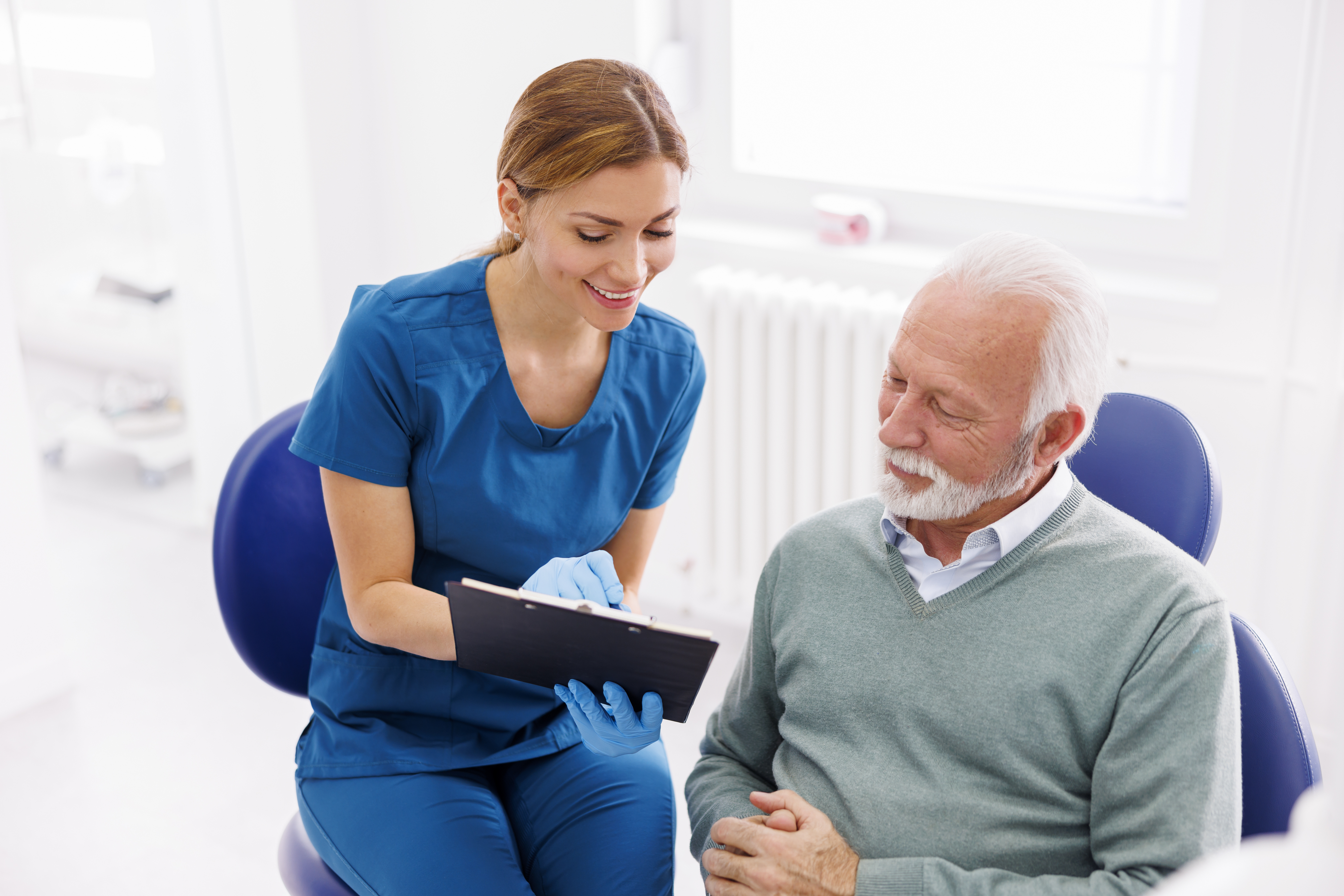 Dentist showing treatment and records to patient inside dental office.