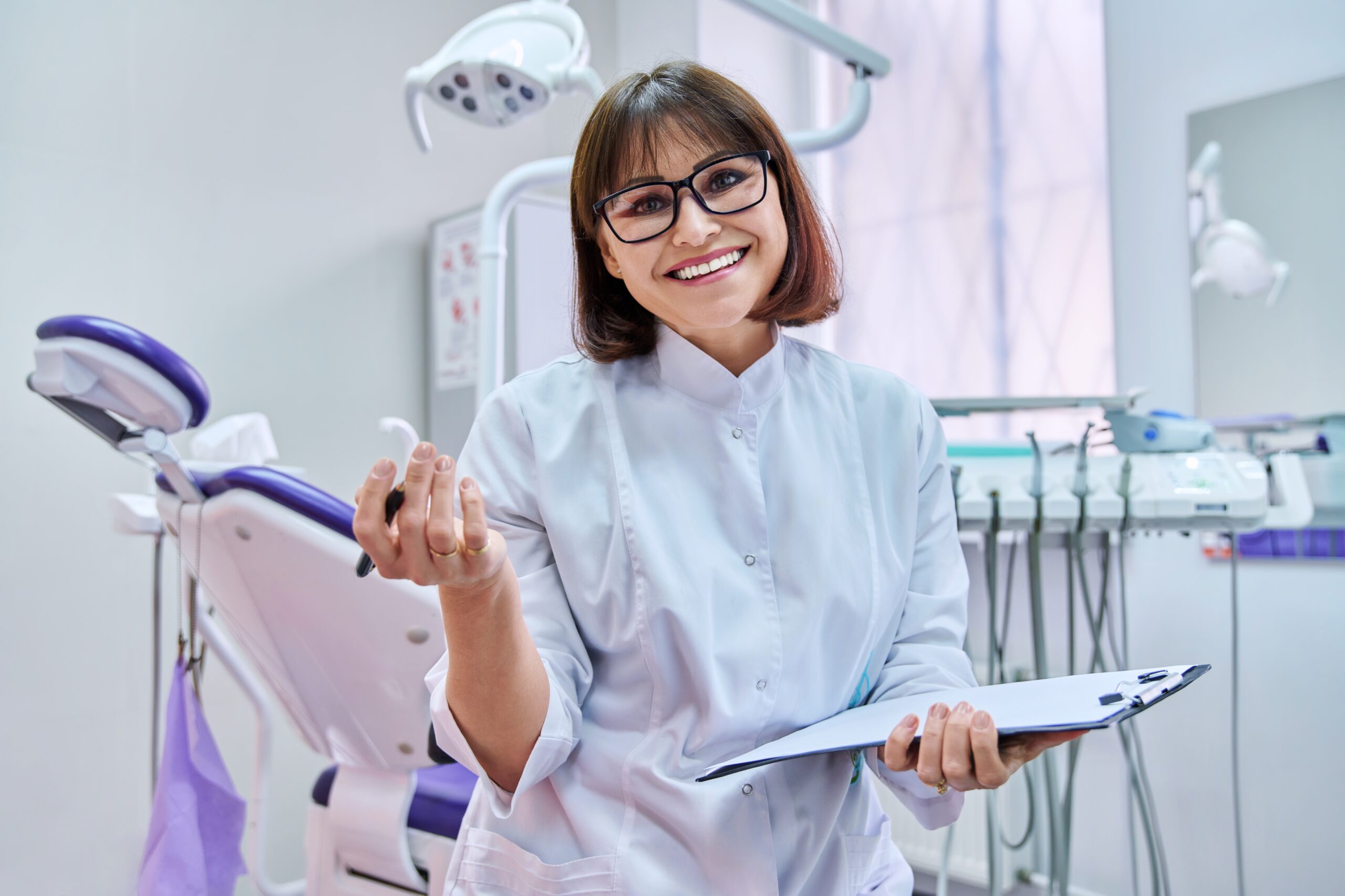 A dentist holding a clipboard and smiling.