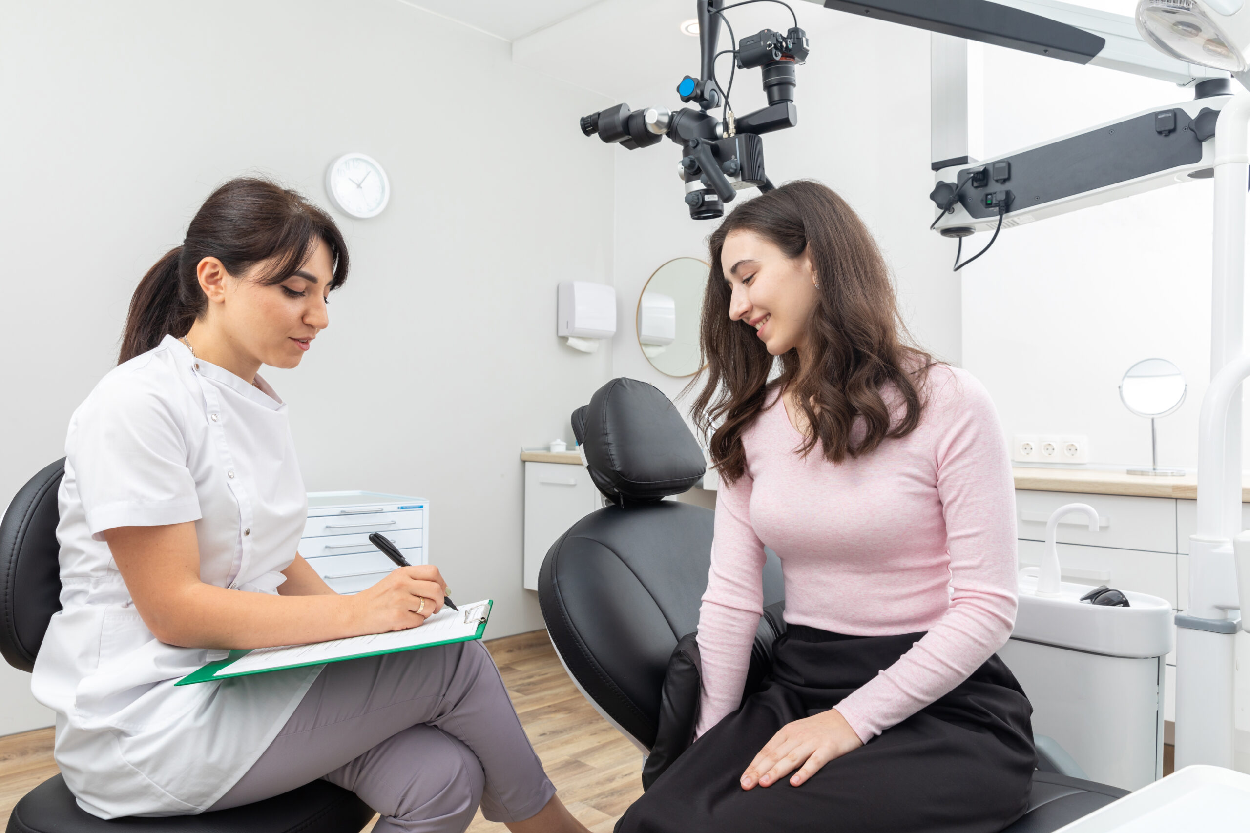 Female Dentist Filling In Papers While Talking To Young Patient