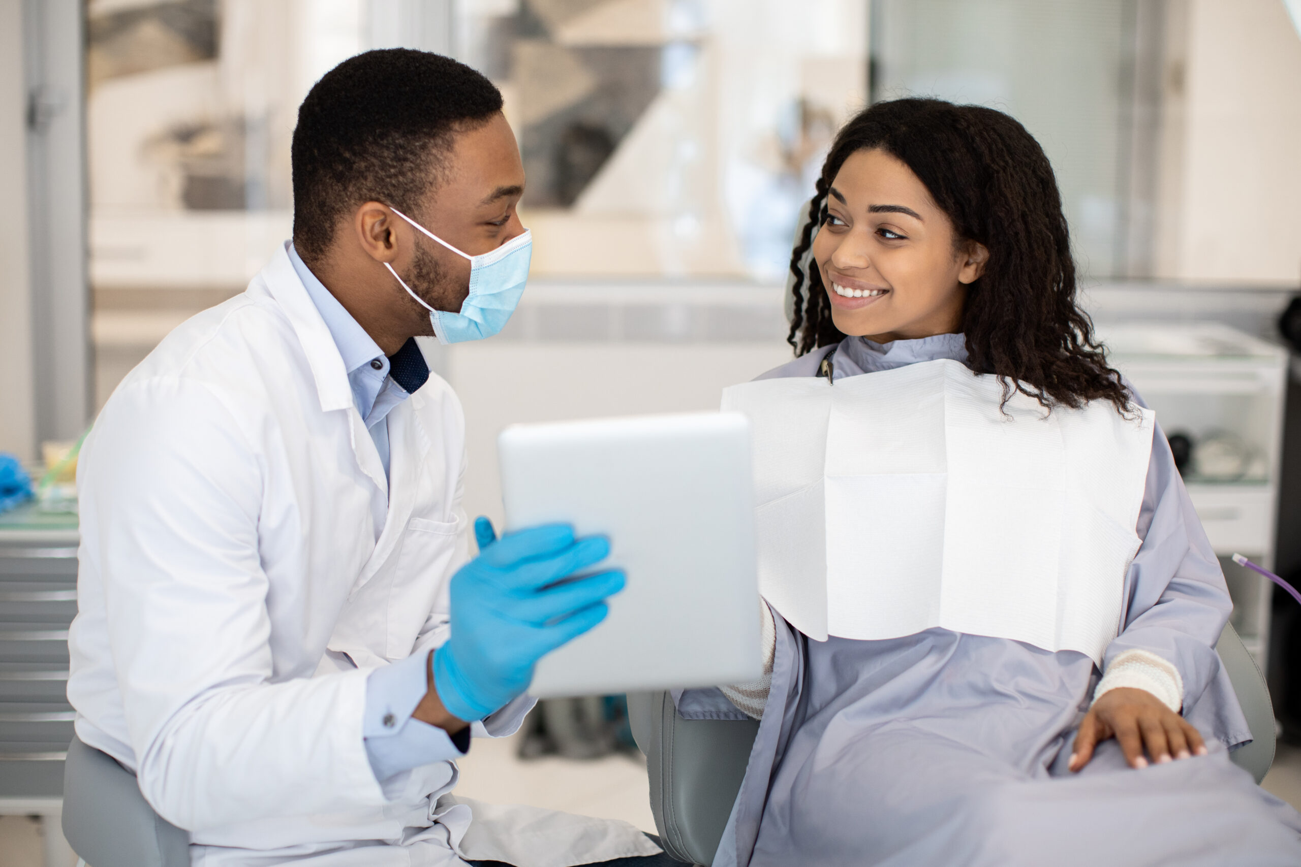 Male dentist using digital tablet to consult a female patient.