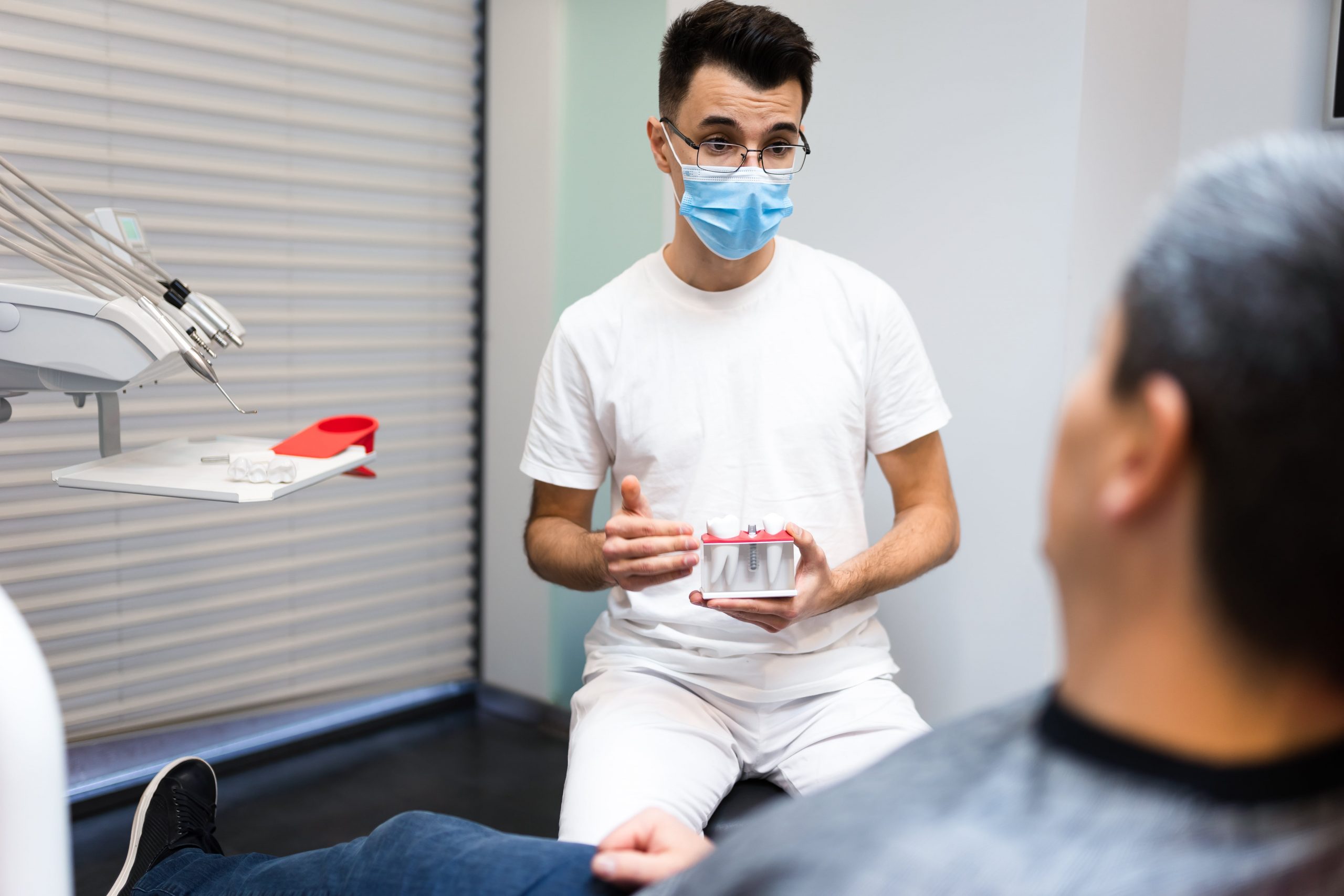 Dentist holding model of crown while talking with a patient.